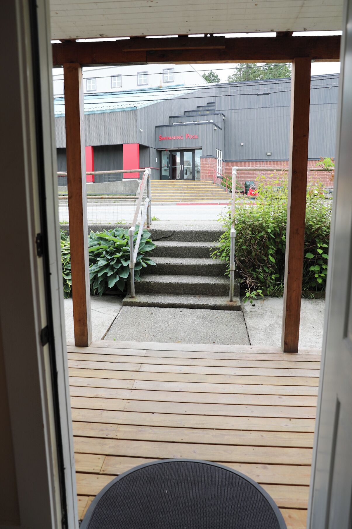 A wooden deck leading to a building with a sign reading 'Swimming Pool'.