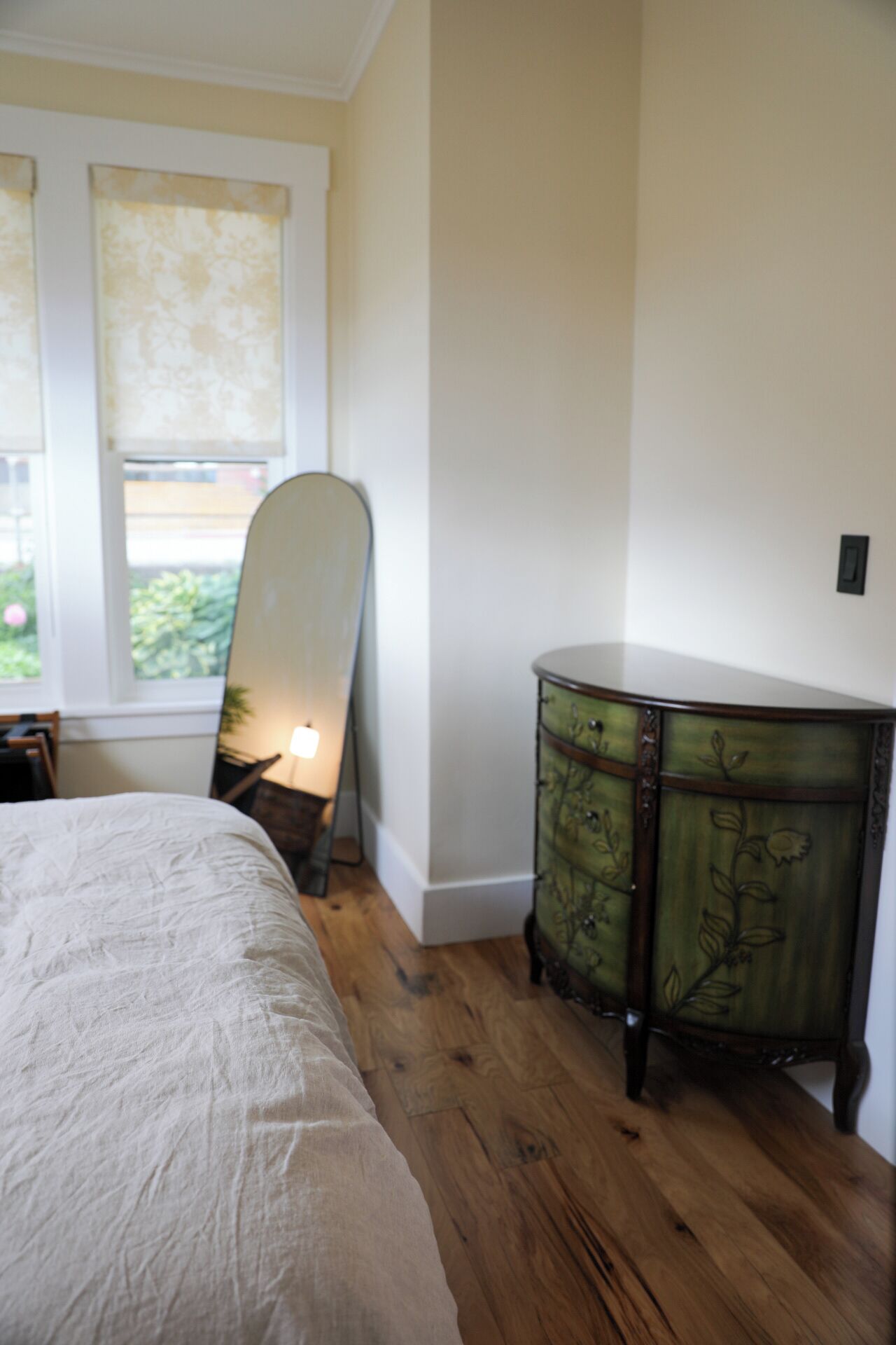 Ein Schlafzimmer mit einem Bett, einem Schminktisch und einem Fenster mit Vorhängen.