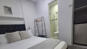 Ett hotellrum med en säng, en garderob och ett badrum som syns genom en öppen dörr.