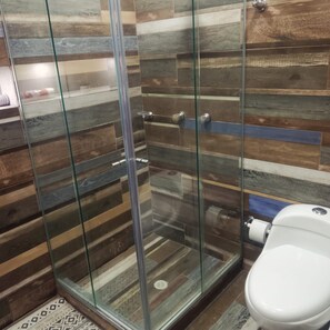A bathroom with a glass shower enclosure, a white toilet, and a patterned floor. - Casa Hotel Sweet Home Apt 203 Grupos (Medellín)