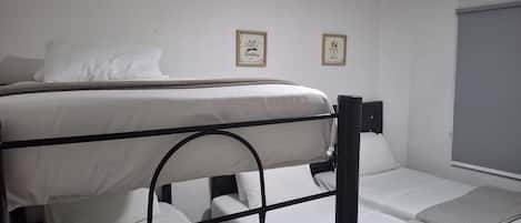 Una cama nido con cabecera y piecera, una mesita de noche y dos cuadros enmarcados en la pared.