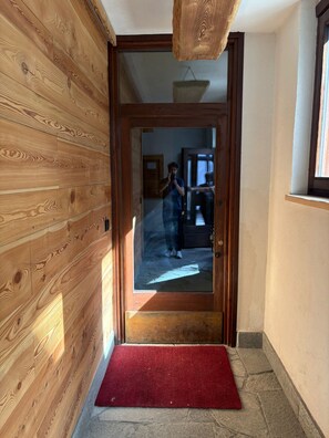A wooden interior hallway with a red carpet leading to a glass door. - Mountain atmosphere at the ski lift departure area (Sauze d'Oulx)
