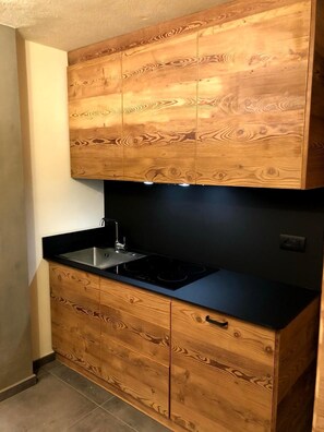 A kitchen with wooden cabinetry and a black countertop. - Mountain atmosphere at the ski lift departure area (Sauze d'Oulx)