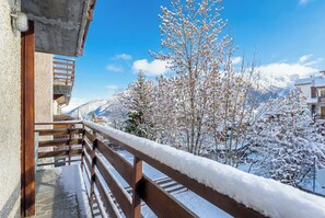A balcony with a wooden railing overlooking a snowy landscape with trees and mountains. - Mountain atmosphere at the ski lift departure area (Sauze d'Oulx)