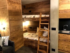 A bunk bed with a ladder, a small desk, and a sink in a wooden room. - Mountain atmosphere at the ski lift departure area (Sauze d'Oulx)