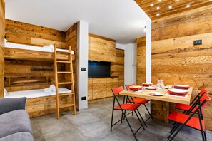 A compact room with a bunk bed, a dining table with chairs, and a television. - Mountain atmosphere at the ski lift departure area (Sauze d'Oulx)