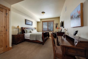 A bedroom with a bed, bedside tables, a desk, a chair, a window with blinds, a painting on the wall, and a ceiling light. - BL6101 | Air Chilling | 4 Pools | 10 Hot Tubs | Winter Shuttle | Close to Slopes (Steamboat Springs)
