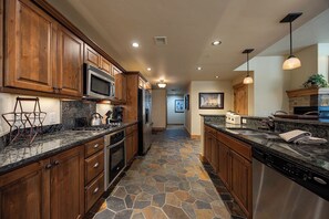 A kitchen with wooden cabinets, a microwave, a stove, and a dishwasher. - BL6101 | Air Chilling | 4 Pools | 10 Hot Tubs | Winter Shuttle | Close to Slopes (Steamboat Springs)