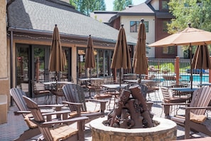 An outdoor patio area with multiple tables and chairs, umbrellas, and a decorative fire pit. - BL6101 | Air Chilling | 4 Pools | 10 Hot Tubs | Winter Shuttle | Close to Slopes (Steamboat Springs)