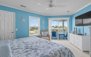 A bedroom with a bed, a ceiling fan, a sliding glass door to a balcony, and a TV mounted on the wall. - North Myrtle Beach Cherry Grove Getaway Beautiful Views Peaceful Coastal Retreat (North Myrtle Beach)