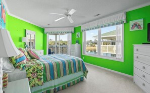 Ein Schlafzimmer mit einem Bett, einer Kommode, einem Deckenventilator und einem Fenster mit Blick.