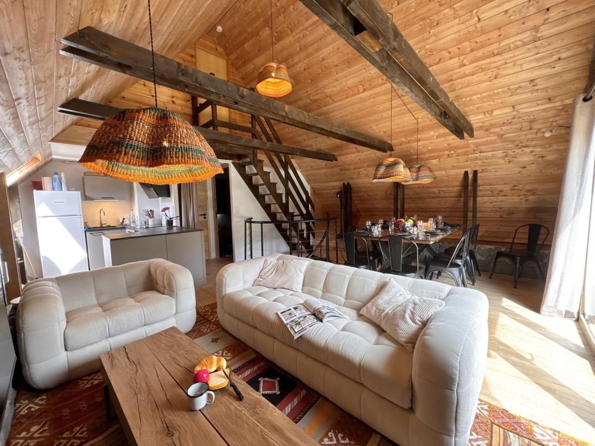 A cozy loft-style living area with a sofa, a wooden coffee table, and hanging pendant lights.
