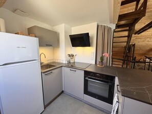 A compact kitchen with a built-in oven, a refrigerator, and a flat-screen TV mounted on the wall. - Chalet, 200m from ski slopes, Ground floor, tv, 110m², Vars (Vars)