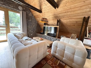 A cozy living room with a stone fireplace, a sofa, a coffee table, and a television. - Chalet, 200m from ski slopes, Ground floor, tv, 110m², Vars (Vars)