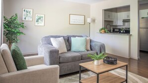 Ein Wohnzimmer mit grauem Sofa, einem kleinen Tisch und einer Topfpflanze.