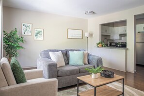 Una sala de estar con un sofá gris, una mesita y una planta en maceta.