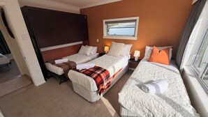 A hotel room with two beds, a window, and a view of the outside. - SQ Property; Autumn Hideaway. Customisable layout for small or large groups (Palmerston North)