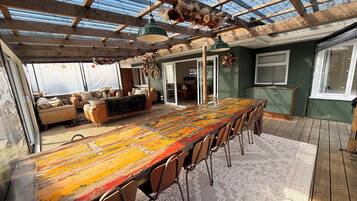 Un vaste espace dédié à la salle à manger, avec une longue table en bois, des chaises et un tapis à motifs.