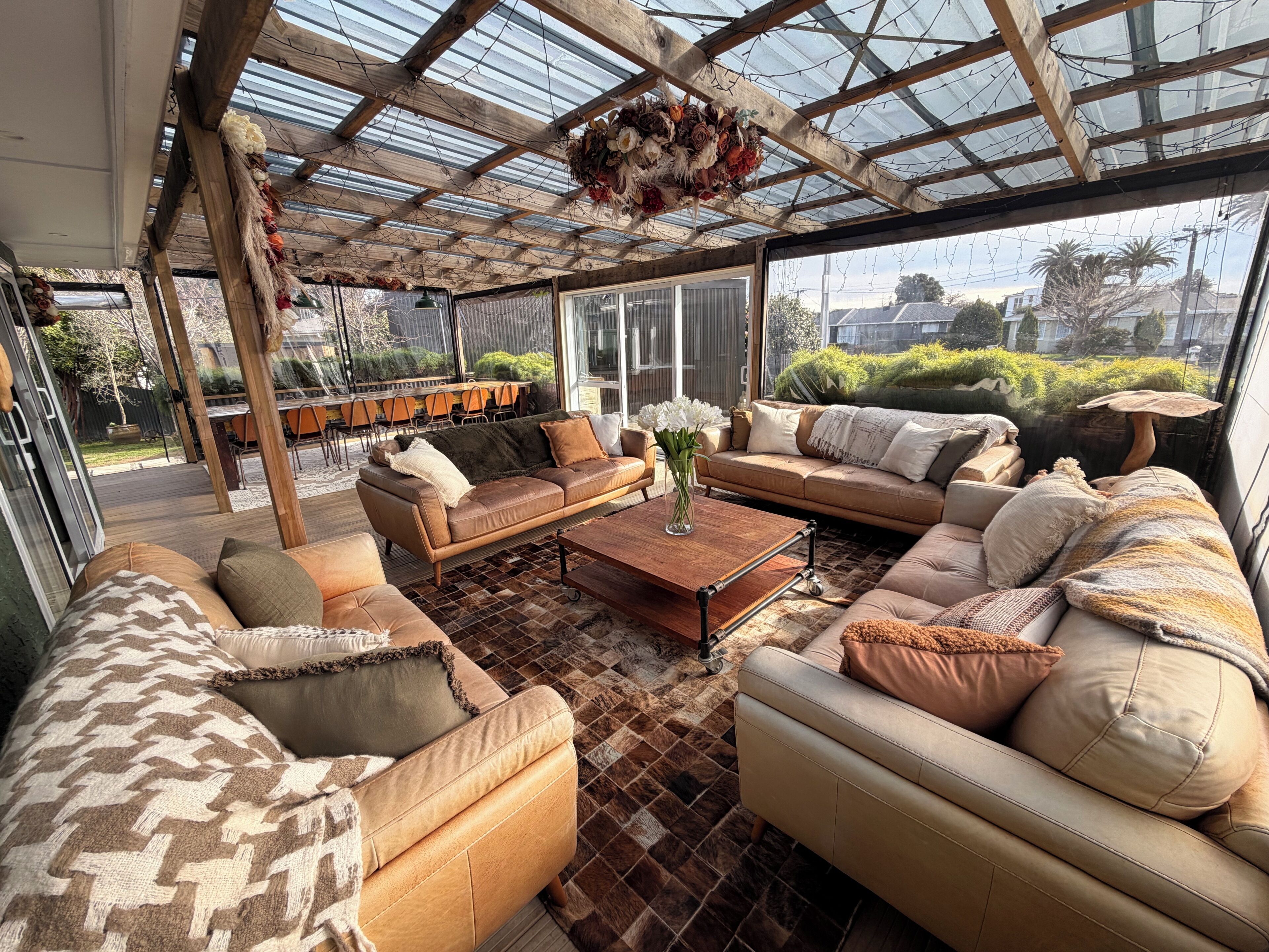 Ein geräumiger Patio-Bereich mit Glasdach, ausgestattet mit Sofas und einem Couchtisch, und Blick ins Freie.
