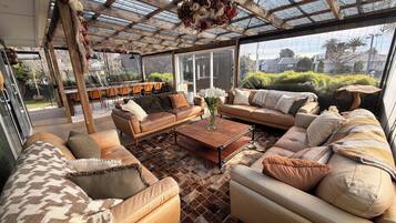 Ein geräumiger Patio-Bereich mit Glasdach, ausgestattet mit Sofas und einem Couchtisch, und Blick ins Freie.