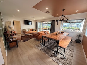 Una sala moderna con una mesa de comedor de madera, sofás de cuero y un ventanal con vistas.