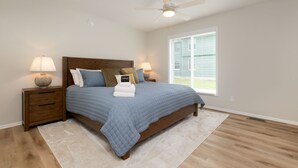 A bedroom with a bed, nightstands, a ceiling fan, and a window.
