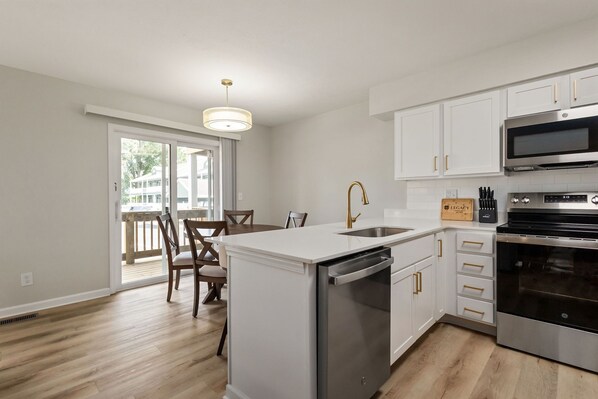 A modern kitchen with white cabinetry, stainless steel appliances, and a central island with a dishwasher.