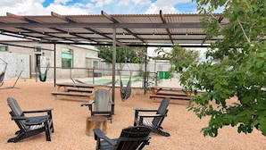 An outdoor seating area with Adirondack chairs, a wooden table, and a hammock. - Bohemio Raconteur: Four Suites + Sauna + Pickleball + Walkable Marfa (Marfa)