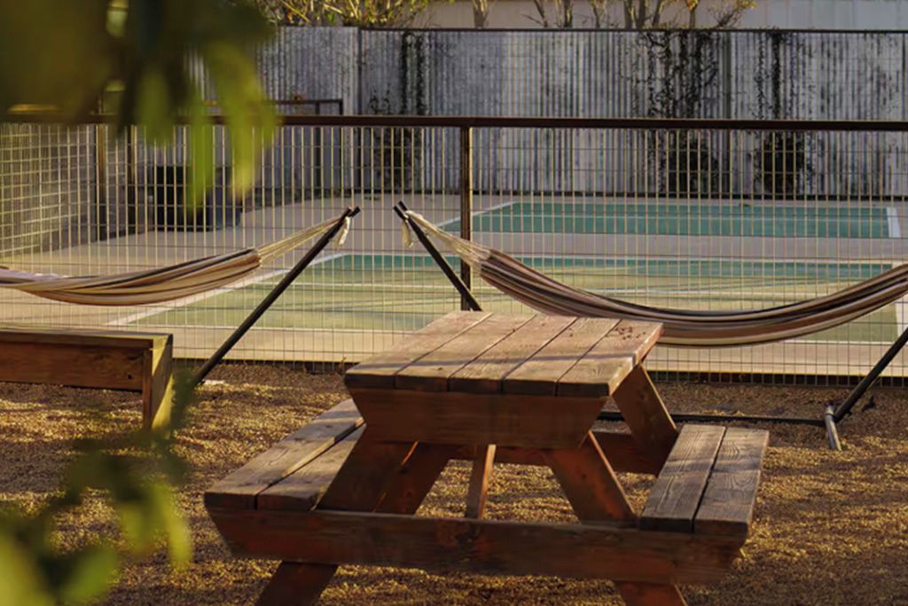 Un hamac et une table de pique-nique sont installés près d’une piscine entourée d’une clôture.