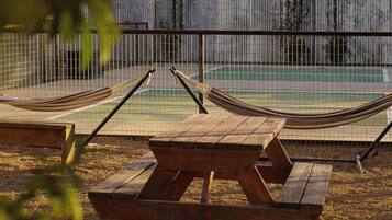Un hamac et une table de pique-nique sont installés près d’une piscine entourée d’une clôture.