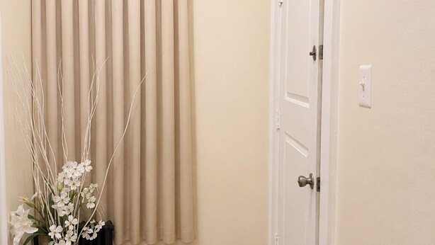 Un pasillo con pared beige, una puerta blanca y un radiador.