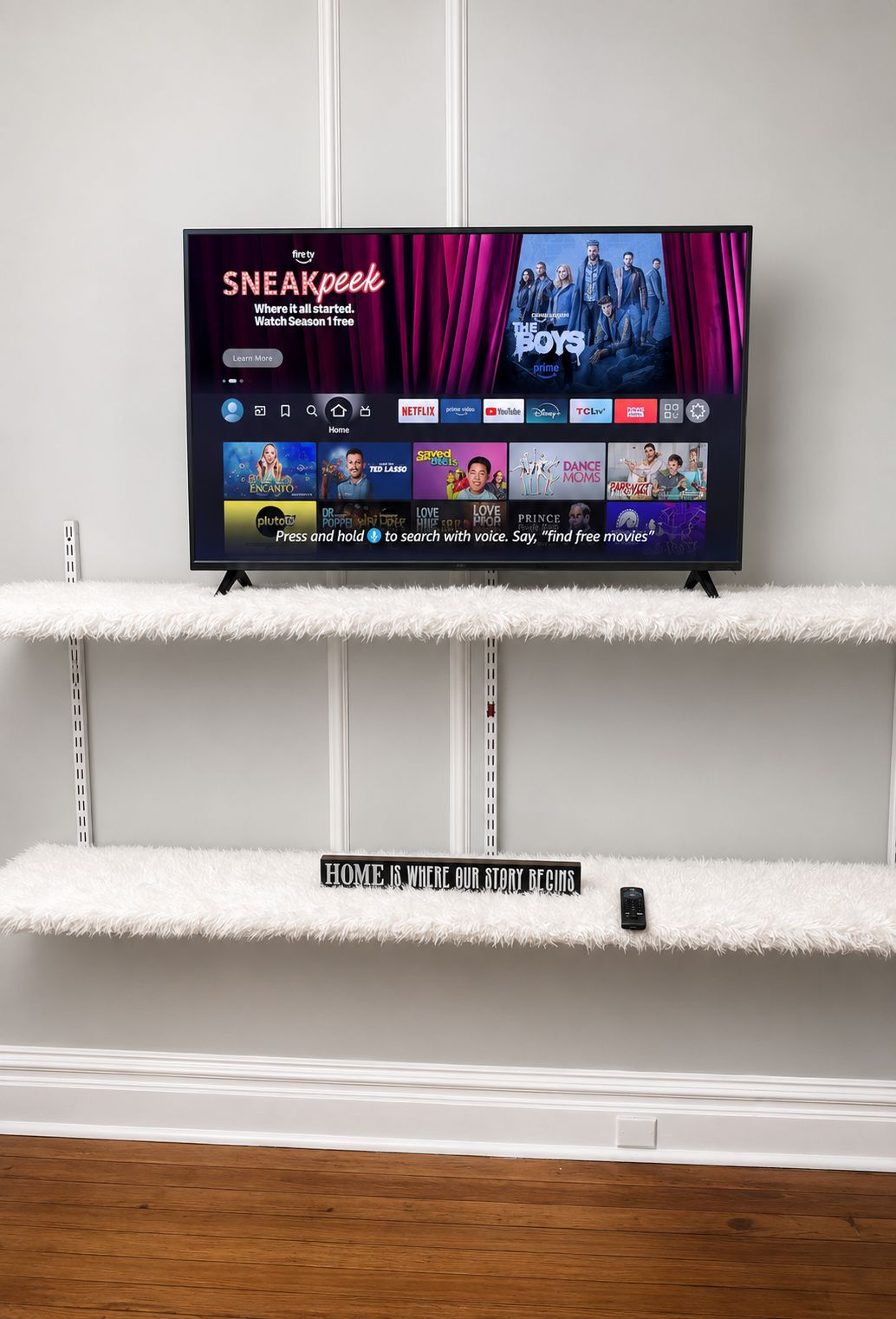 A television on a white shelf with a sign below stating 'HOME IS WHERE OUR STORY BEGINS.'