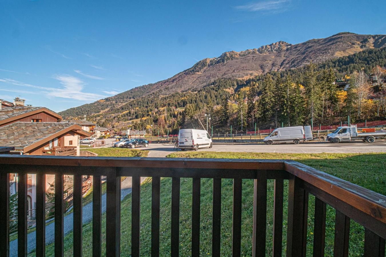 A mountain view with a parking lot, a white van, and a building with a sloped roof.