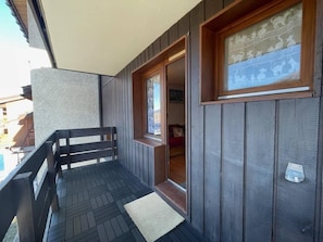 A balcony with a wooden railing, a small window with a decorative frame, and a door leading to an interior space. - Ski-in/ski-out & foot of the slopes, 1st floor, balcony, ski locker, 23m², Valmorel (Valmorel)