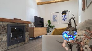A modern living room with a fireplace, wooden furniture, and decorative wall art. - Stone house with an olive grove, a movie theater, and a sim racing setup—sleeps 8 near Serra da Estrela (Distrito da Guarda)