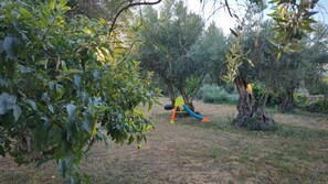 A garden with a swing set, trees, and a grassy area. - Stone house with an olive grove, a movie theater, and a sim racing setup—sleeps 8 near Serra da Estrela (Distrito da Guarda)