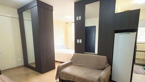 Une pièce comprenant un lit, un canapé, un miroir et une armoire.