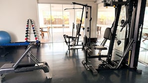 Une salle de sport équipée de matériel d’exercice, avec un ballon d’exercice bleu, et une vue sur l’extérieur grâce à de grandes fenêtres.
