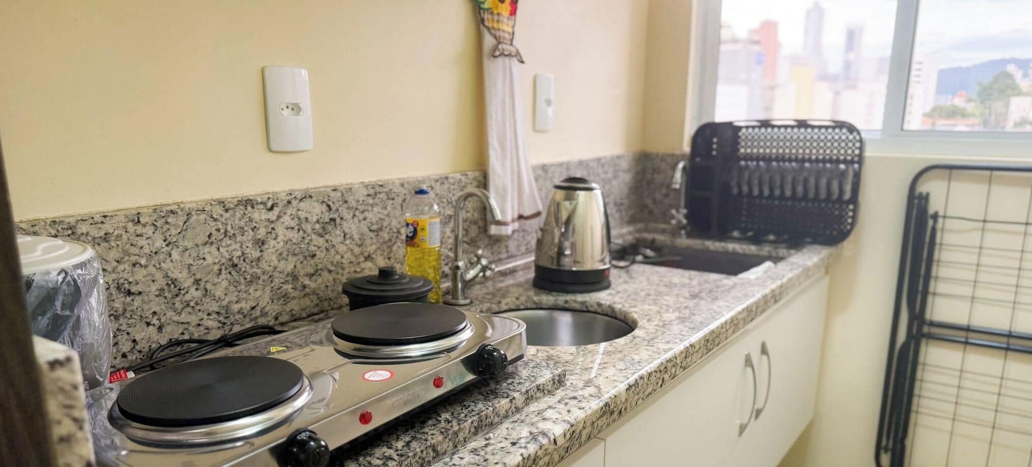 A kitchen with a granite countertop, a kettle, a toaster, and a kettle on the stove.
