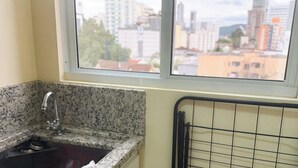 Une cuisine dotée d’un plan de travail en granit, d’un robinet en acier inoxydable et d’une fenêtre offrant une vue sur la ville.