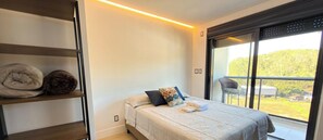 A bedroom with a bed, pillows, a window with a view, and shelves with folded blankets. - ASA Itajai Ressacada 3BR Near Br101 Beaches (Itajai)