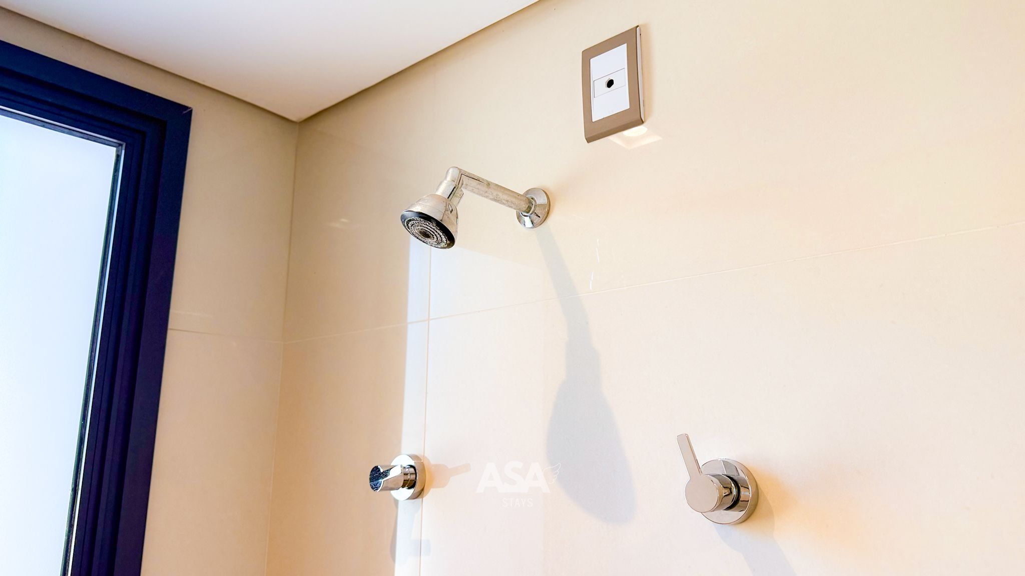 A shower with a handheld showerhead and a wall-mounted control valve.