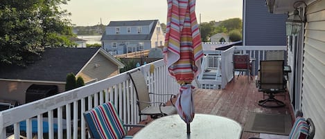 A deck with outdoor furniture, including chairs and a table, and an umbrella.
