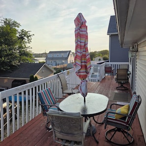 A deck with outdoor furniture, including chairs and a table, and an umbrella. - 1-bedroom apartment  in Point Pleasant Beach ,walking distance to beach n boards (Point Pleasant Beach)