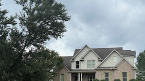 A two-story house with a front porch, a brick facade, and a large tree in the foreground. - Private 4BR Oxford Home Minutes from Ole Miss & Square (Oxford)