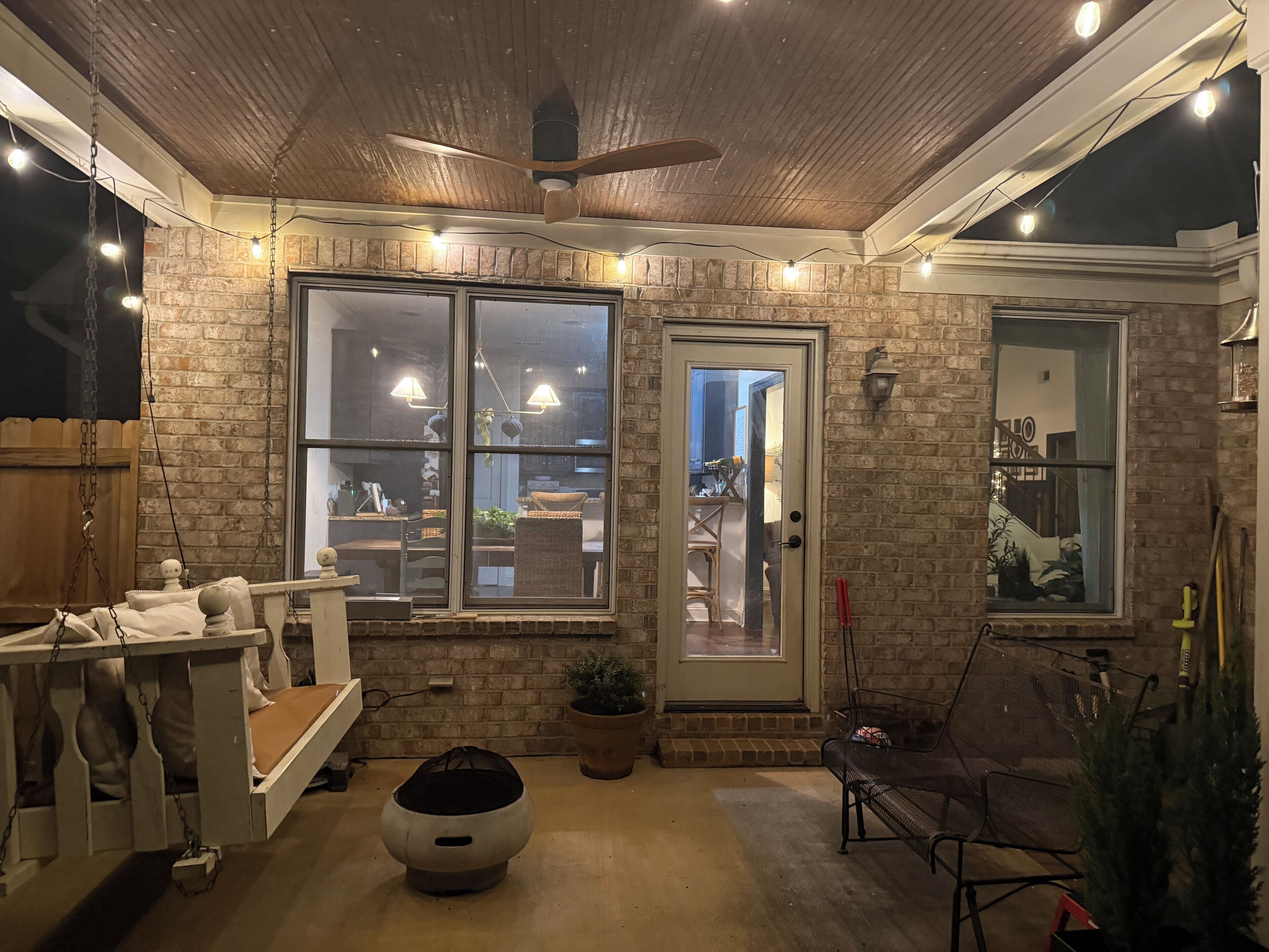 A cozy room with a wooden ceiling, a large window, a door, and a small seating area.