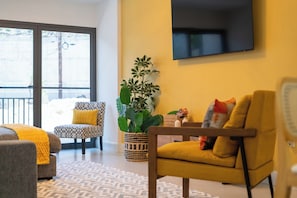 A modern living room with a sofa, armchair, and a large potted plant. - SOL Euphoria Ocho Rios walk to the beach (Ocho Rios)