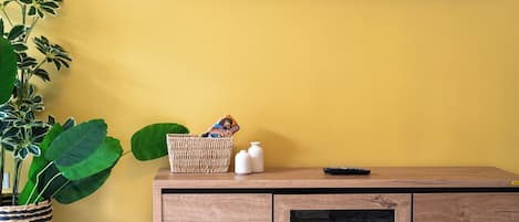 A room with a wooden cabinet, a television mounted on the wall, and a potted plant.
