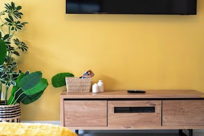 A room with a wooden cabinet, a television mounted on the wall, and a potted plant. - SOL Euphoria Ocho Rios walk to the beach (Ocho Rios)