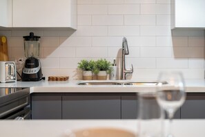 A kitchen with a white countertop, a blender, a toaster, a sink, and a wine glass. - SOL Euphoria Ocho Rios walk to the beach (Ocho Rios)